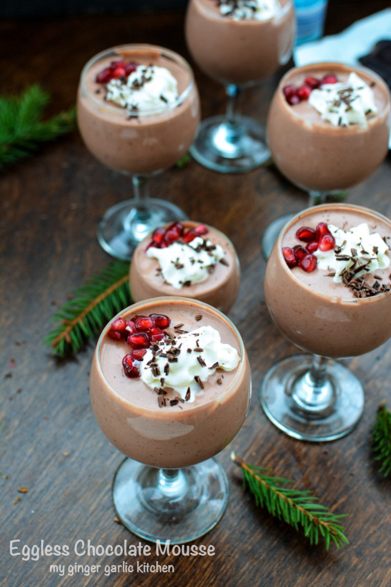 several glasses of ceggless chocolate mousse with whipped cream and pomegranate