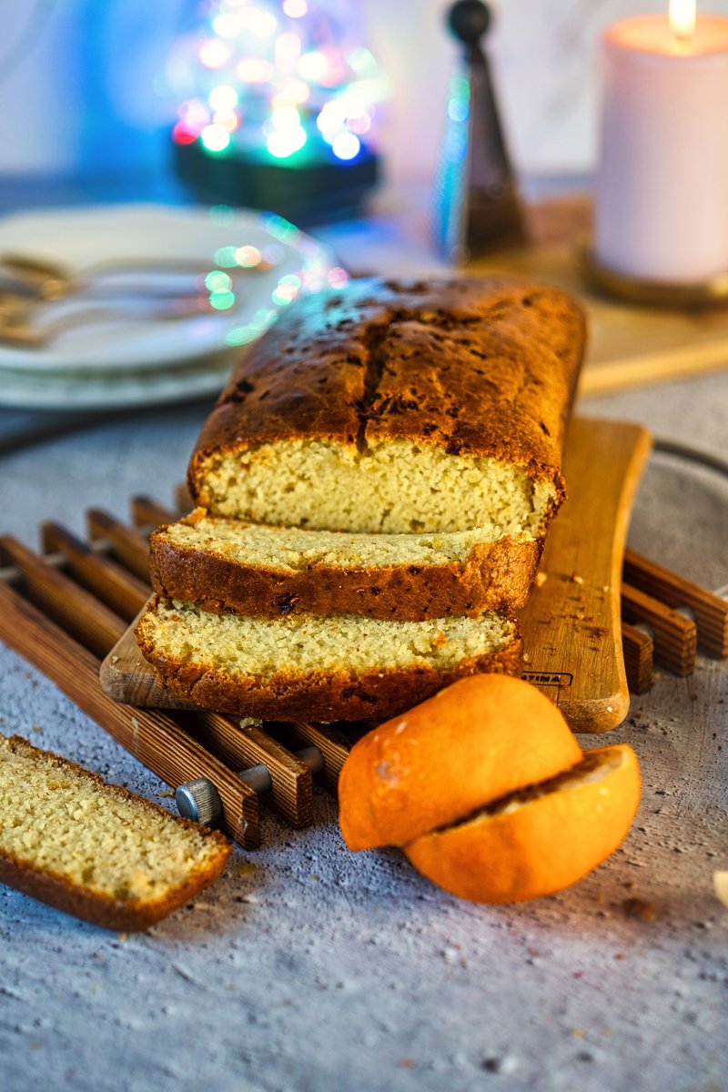  Eggless orange cake sliced on a wooden board, with a single slice and some orange slices in the foreground.