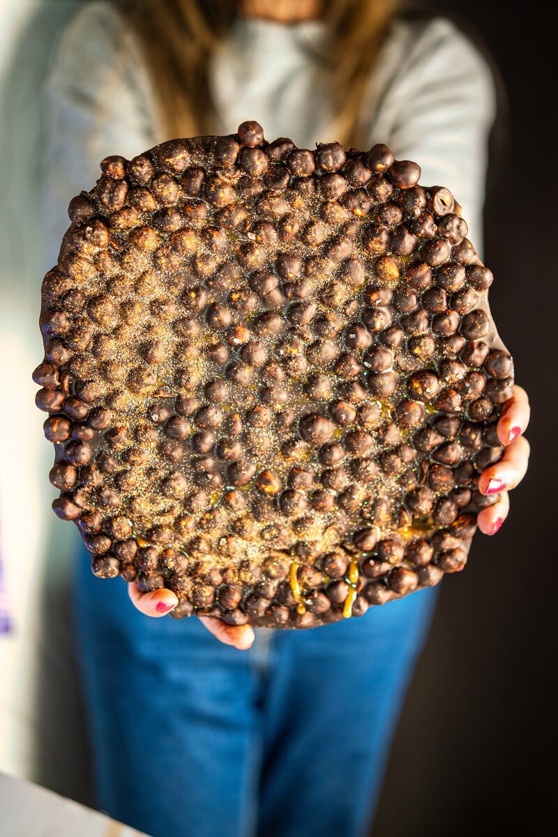Espresso hazelnut dark chocolate bark held in hands, no-bake vegan chocolate bark with roasted hazelnuts and caramel drizzle