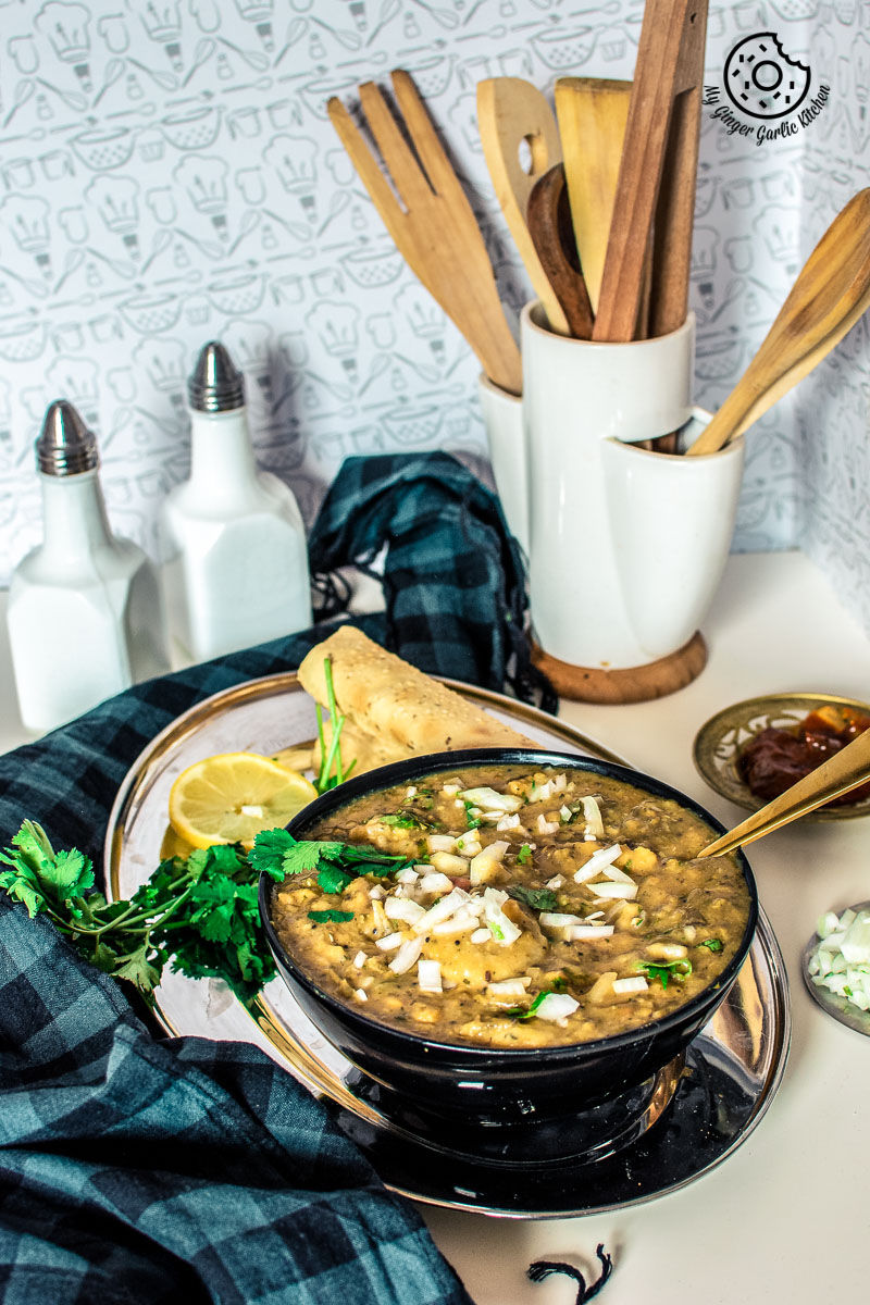 there is a bowl of rajasthani dal dhokli on a plate with a spoon and a napkin