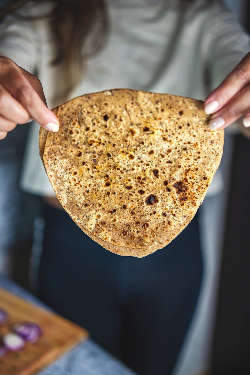 Triangle shaped flaxseed paratha showing soft texture, whole wheat alsi paratha cooked on tava.
