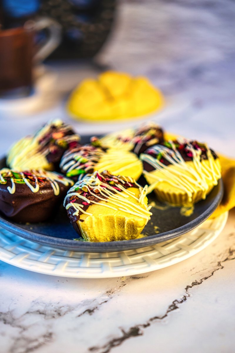 Easy frozen mango lassi bites coated in dark chocolate and decorated with pistachios and rose petals