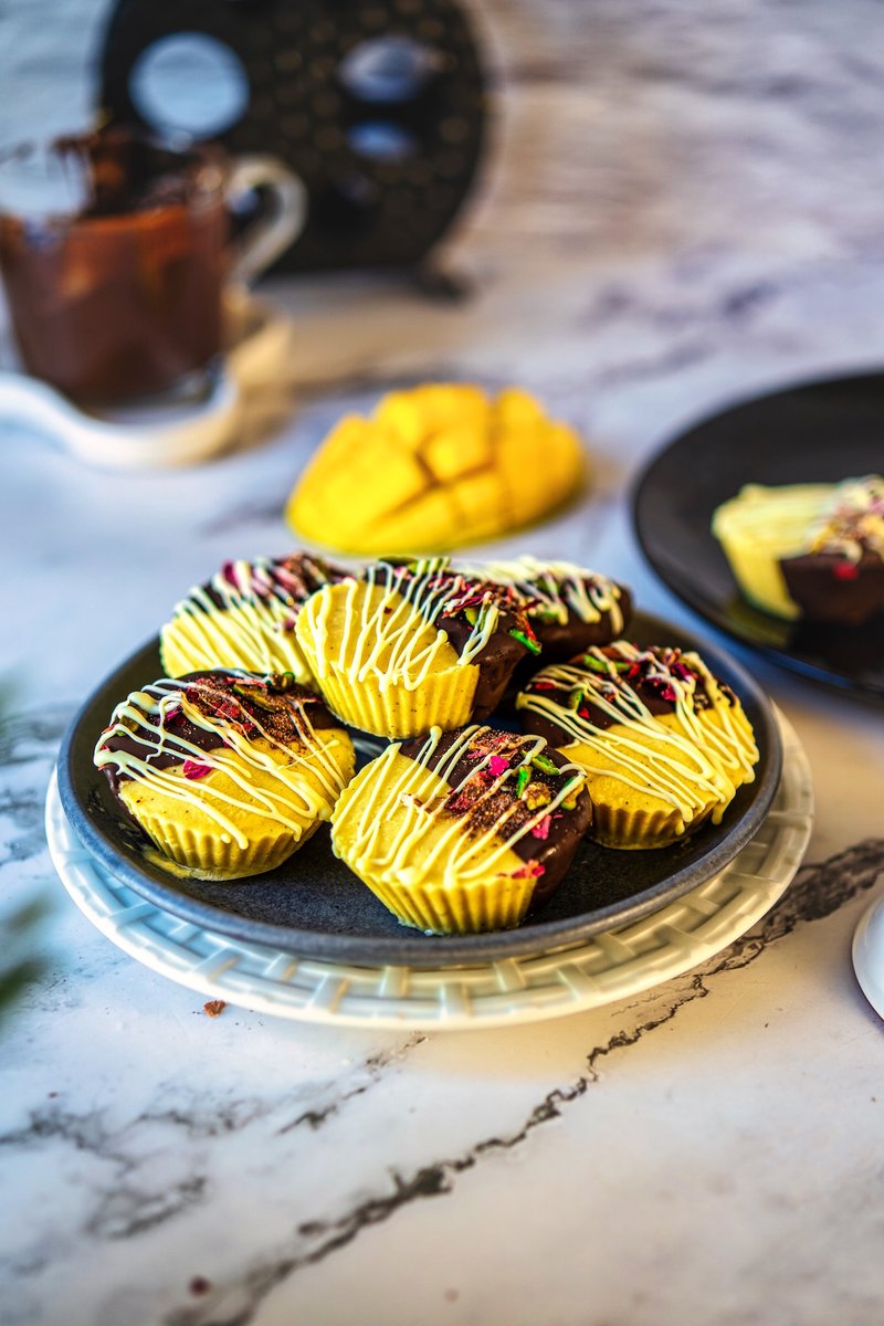 Creamy frozen mango lassi bites with dark chocolate coating served on a plate with fresh mango