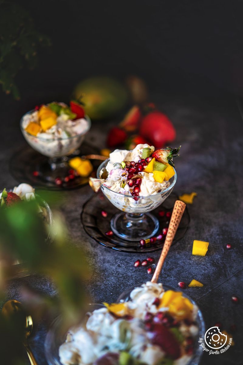 two fruit cream dessert glasses topped with fresh fruits