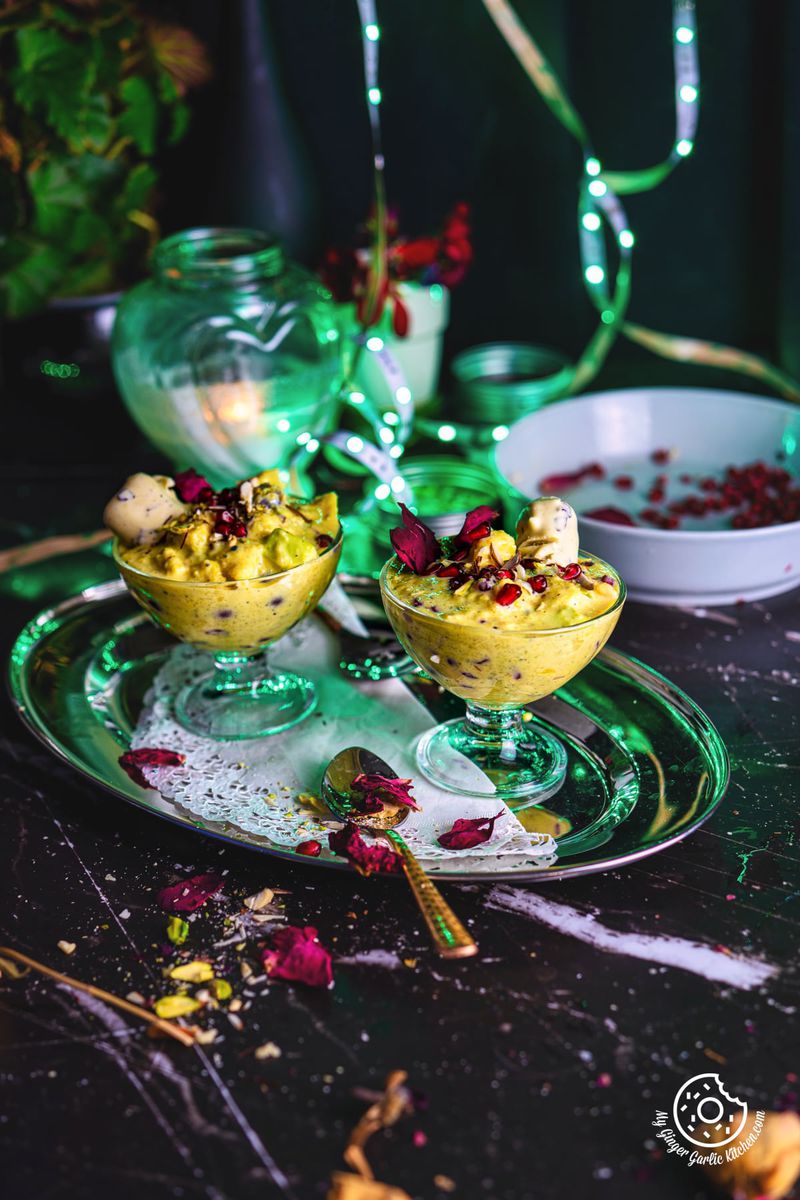 2 fruit rabri dessert glasses in a steel tray with a candle in background