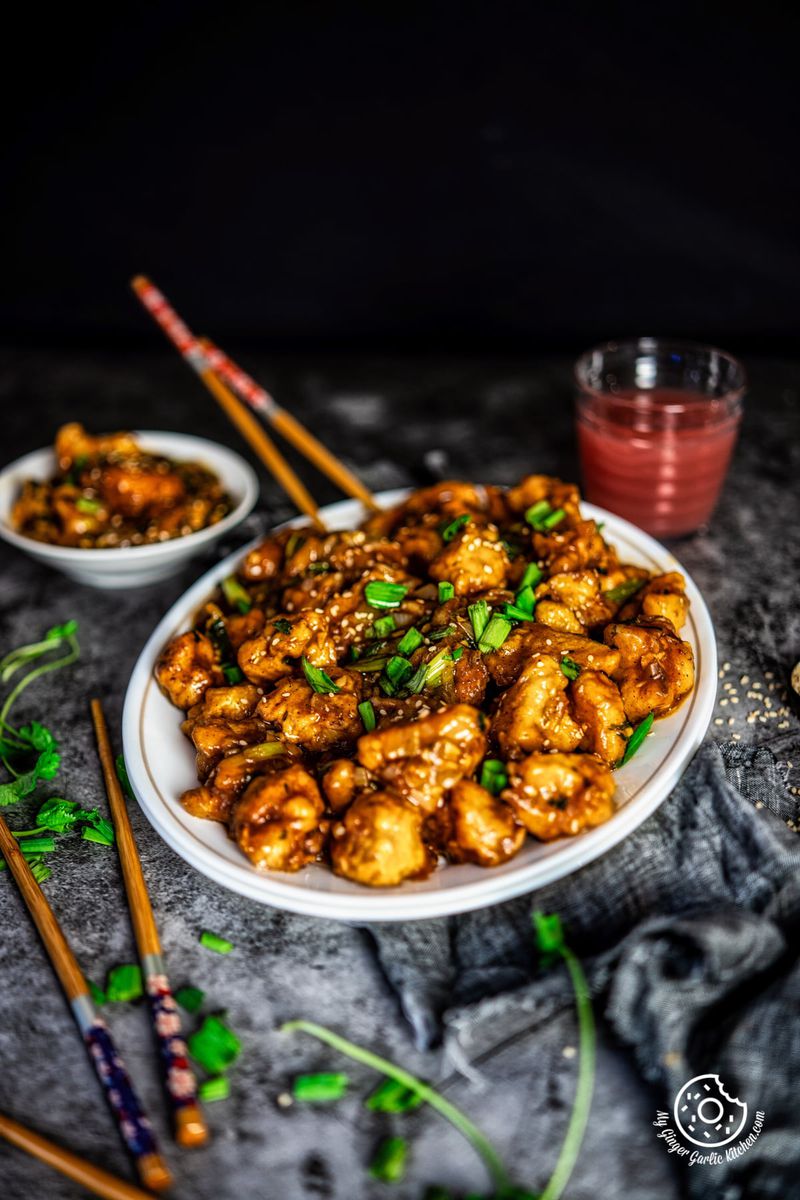 gobi manchurian a white oval plate and some wooden chopsticks on side