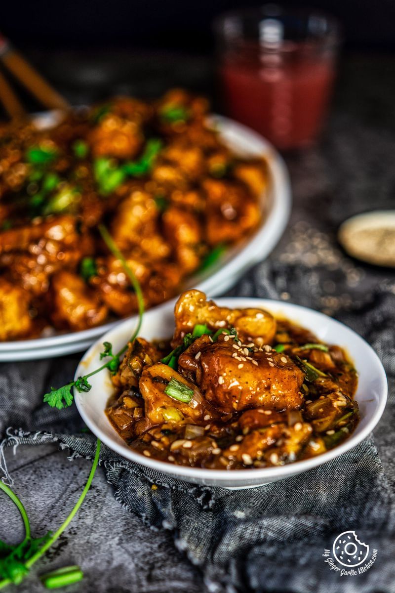 gobi manchurian topped with sesame seeds served in a white bowl