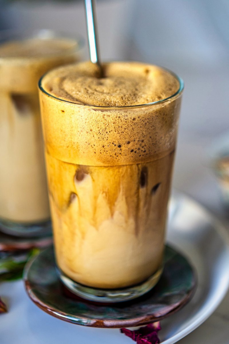 Close-up of a creamy and frothy Greek frappe in a glass with visible layers of coffee and milk.