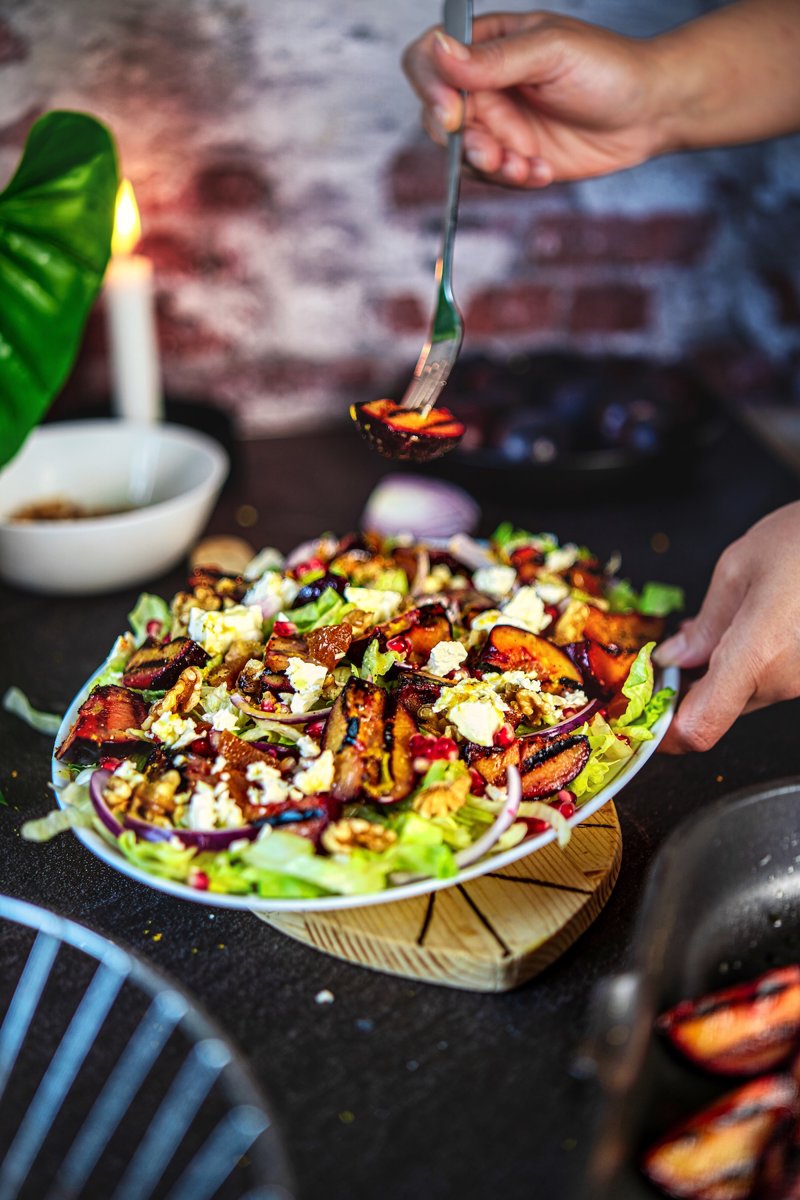 Grilled plum salad with feta, walnuts, pomegranate, and caramelized plums served on a platter