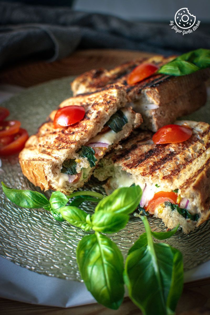 grilled tomato mozzarella sandwiches with tomatoes and basil on a plate