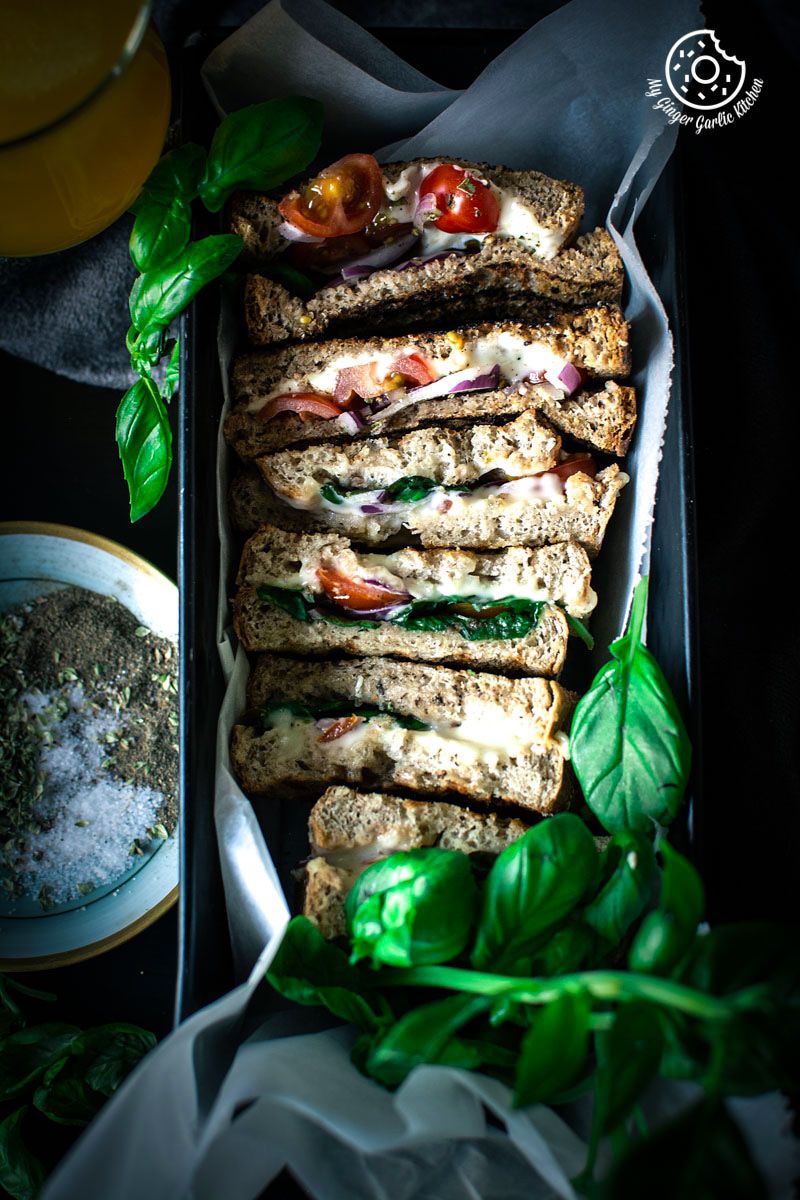 a tray with grilled tomato mozzarella sandwiches and a bowl of spices