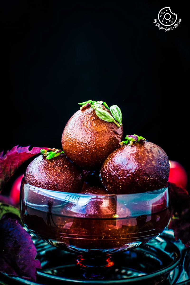 three gulab jamuns in a bowl on a table