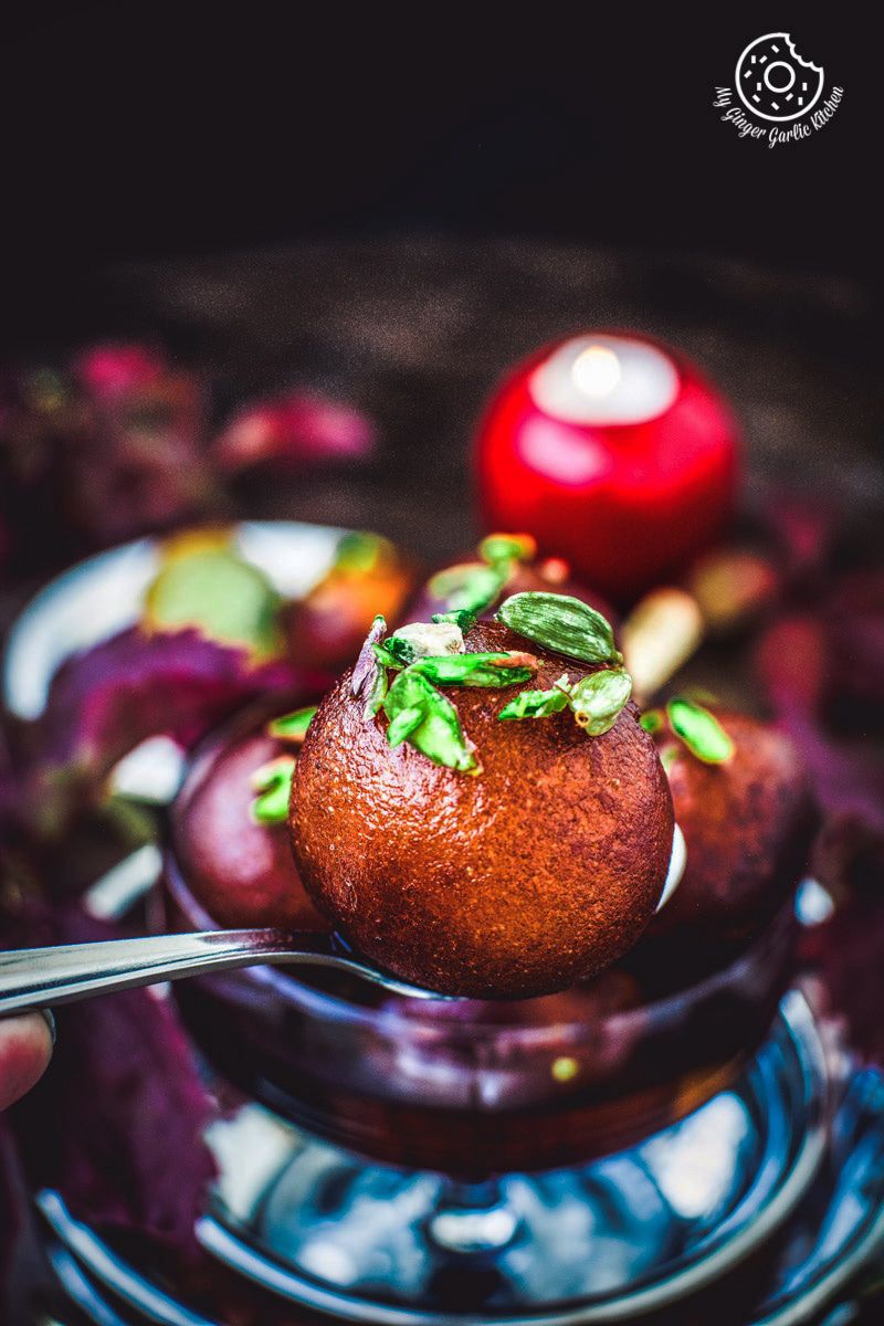 closeup of a spoon with a gulab jamun on it
