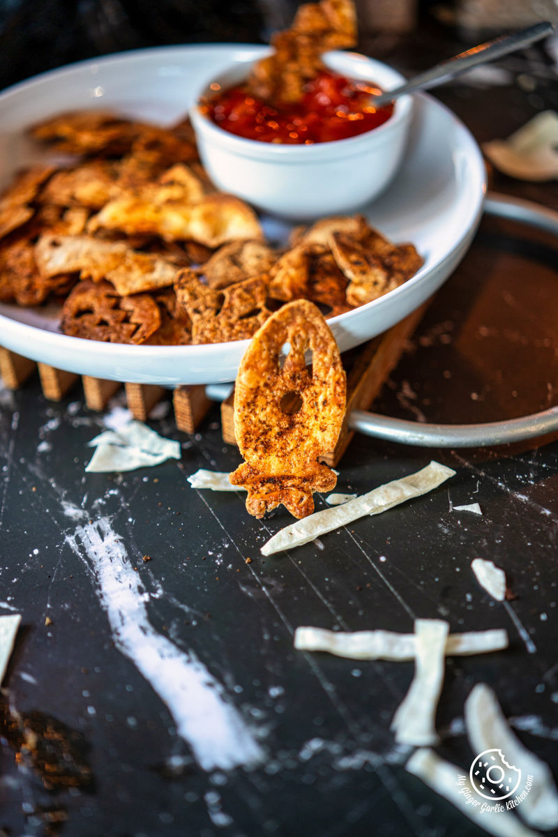 photo of a plate of halloween tortilla chips with a bowl of tomato salsa on it