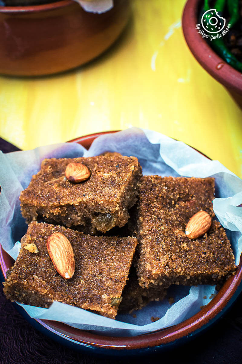 there are a plate of suji halwa bars that topped with almonds