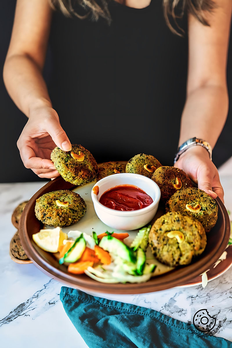 a female holding crispy hara bhara kababs plate with ketchup and salad