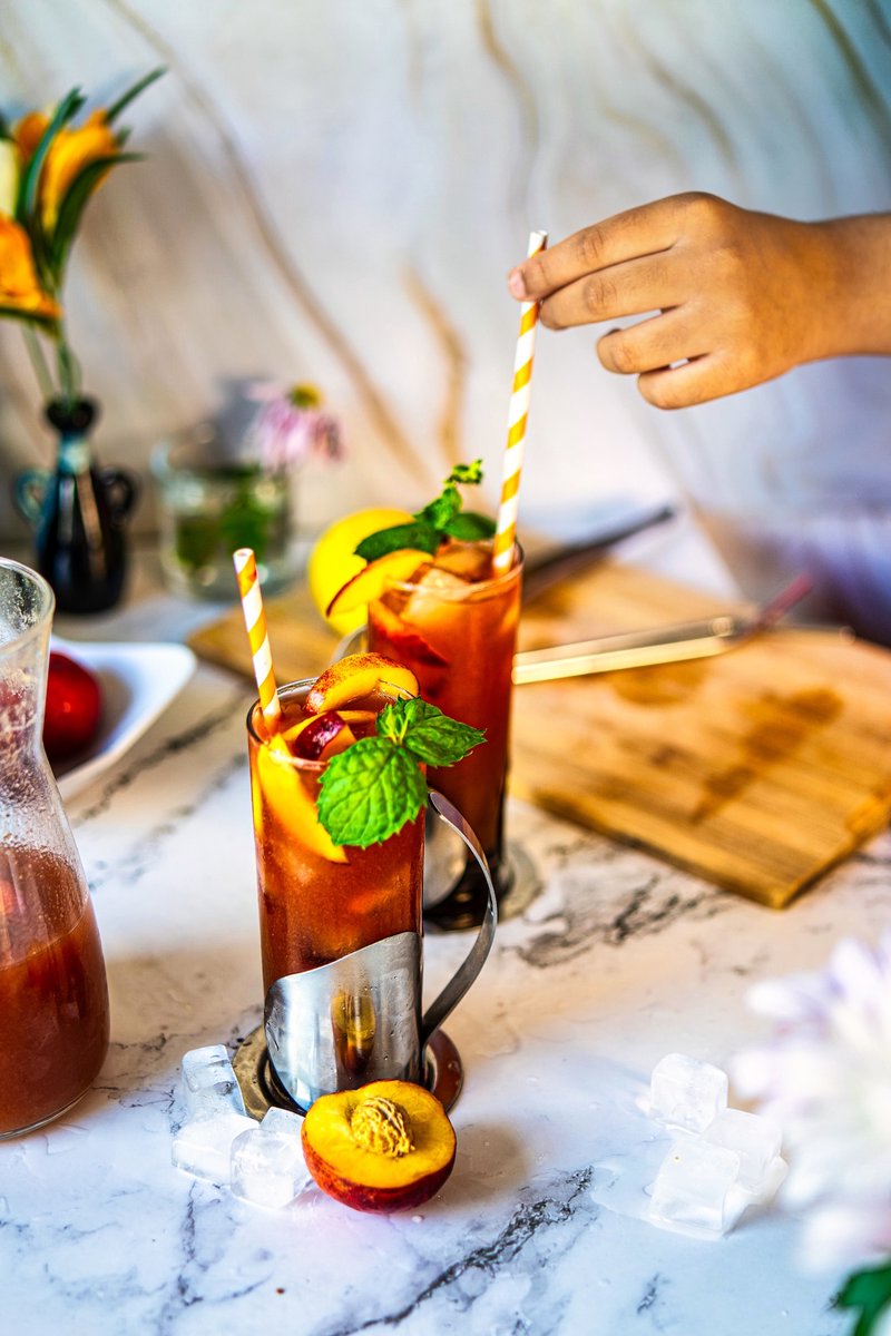 Close-up of homemade peach iced tea with fresh peach slices, mint and ice