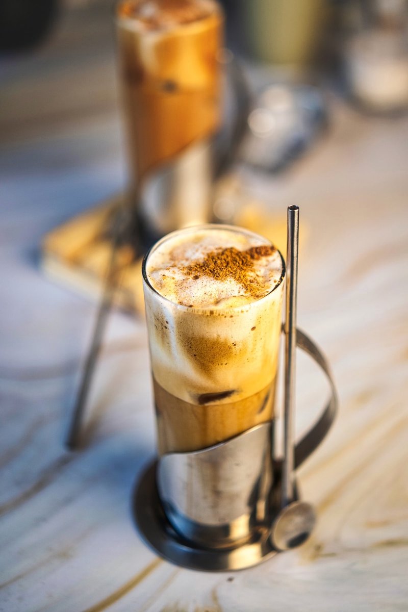 Creamy Honey Cinnamon Iced Coffee topped with frothy coffee foam and cinnamon, served with a metal straw