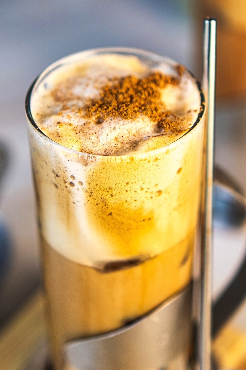 Honey Cinnamon Iced Coffee close-up showing creamy cinnamon milk, fluffy coffee foam, ice cubes, and cinnamon topping
