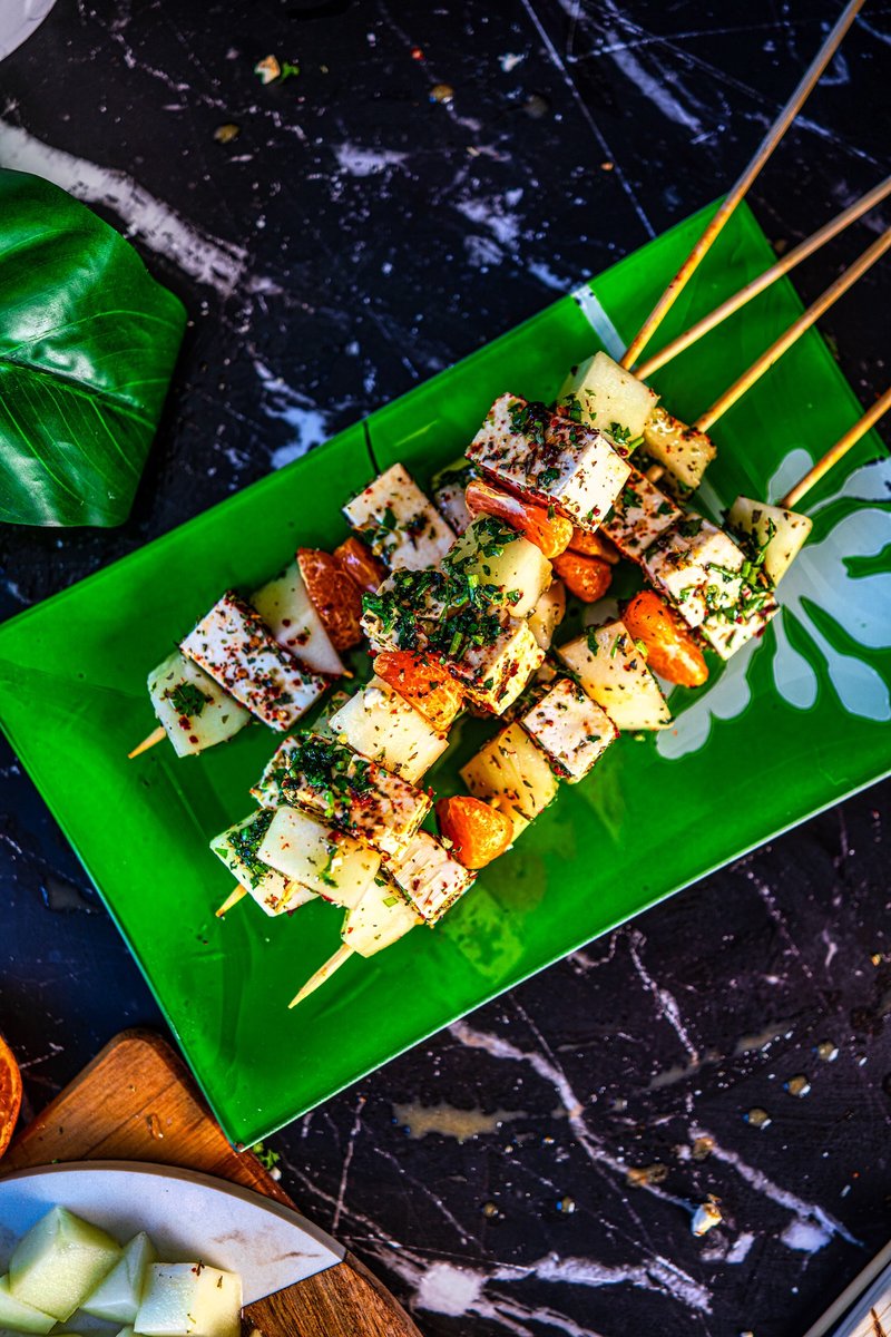 Honeydew Melon Feta Skewers arranged on a green platter with fresh herbs and orange mustard vinaigrette, perfect for summer parties
