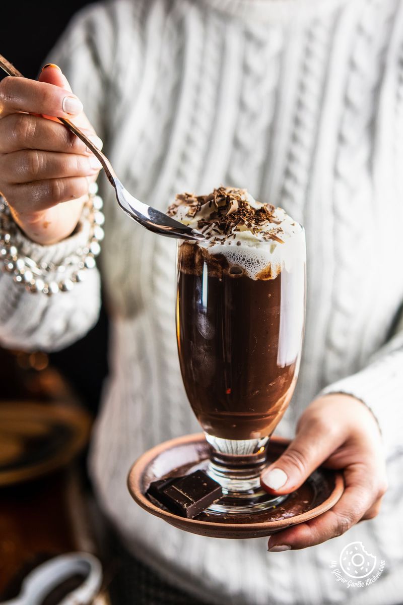 A female holding a transparent tall glass of Italian Hot Chocolate