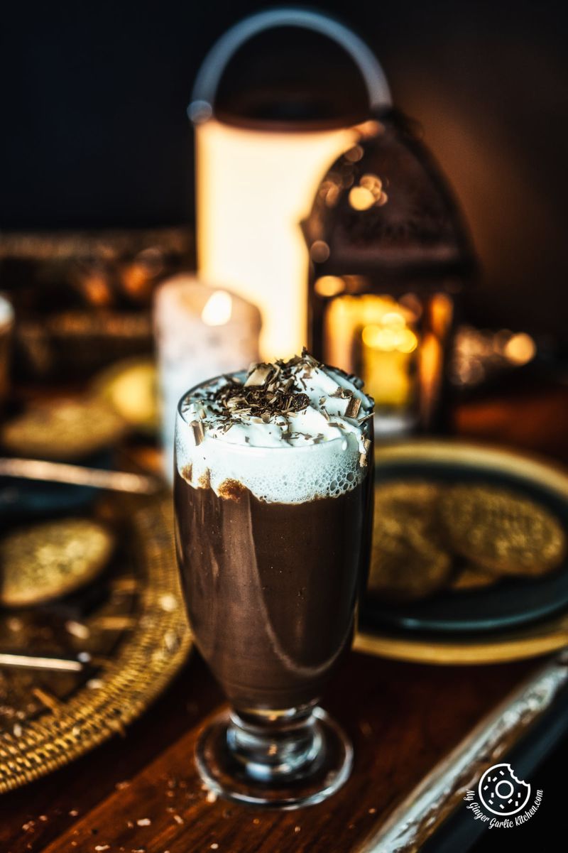 Italian Hot Chocolate with whipped cream and chocolate shavings in a transparent tall glass