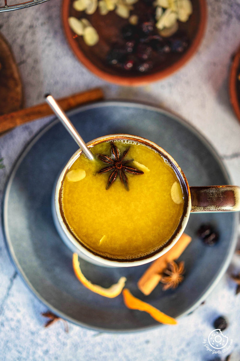 closeup photo of a cup of mulled orange juice with a spoon and a spoon in it