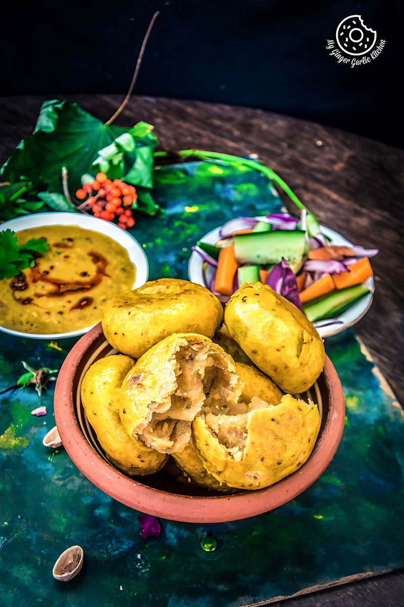 there is a bowl of bafla baati on a table with a bowl of dal