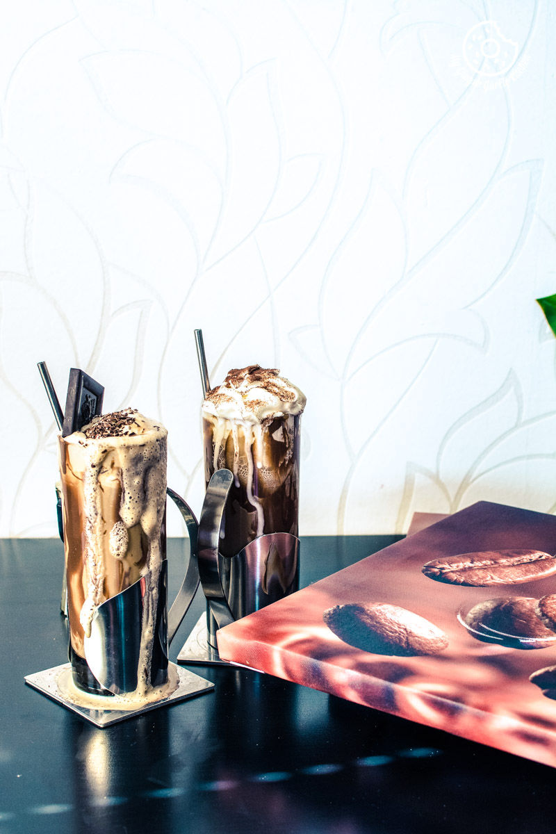 there are two glasses of cold coffee on a table with a book