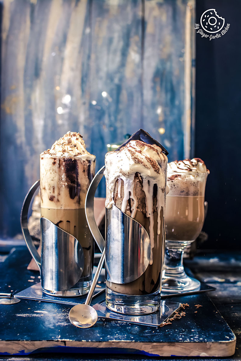 there are three glasses of cold coffee with whipped cream and chocolate sauce