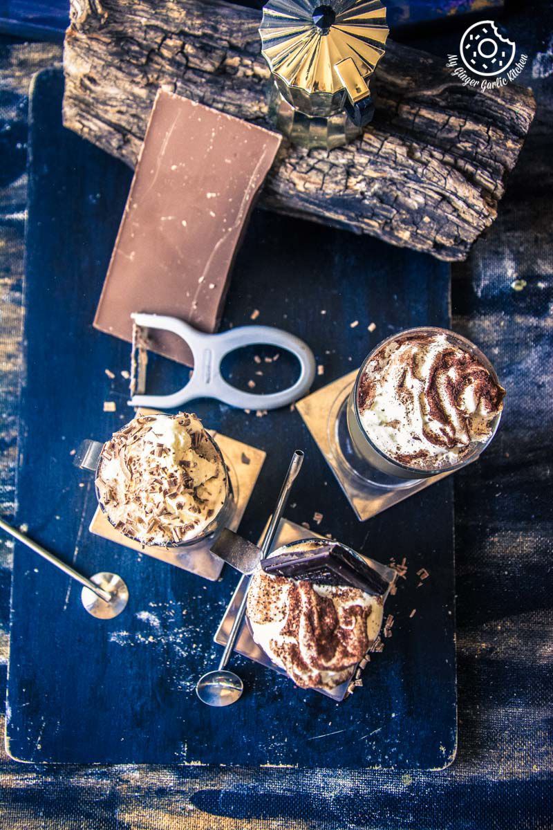 there are three cold coffee glasses on a blue tray with a pair of scissors