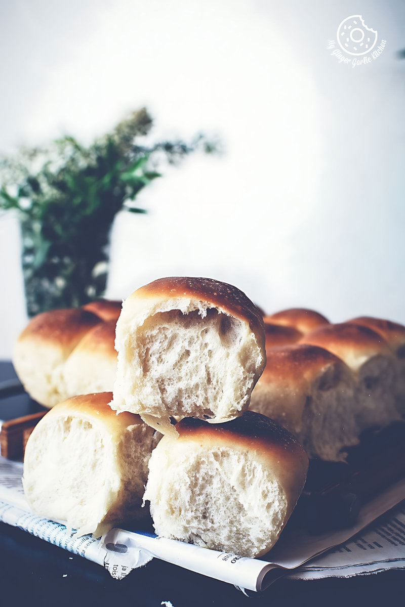 a bunch of soft, fluffy, spongy ladi pav or dinner rolls on a wooden plate on a table
