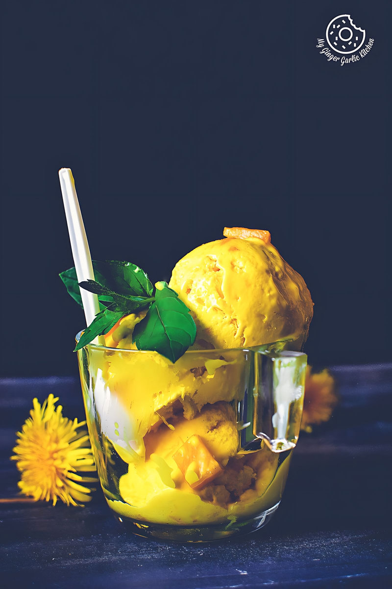 a glass cup filled with mango ice cream and a white spoon