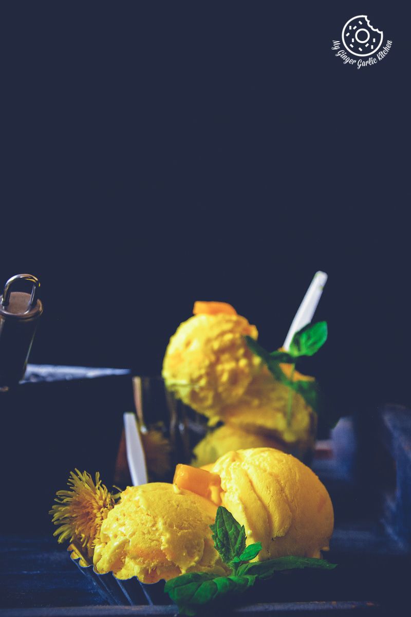 three scoops of mango ice cream topped with fresh mint on a table