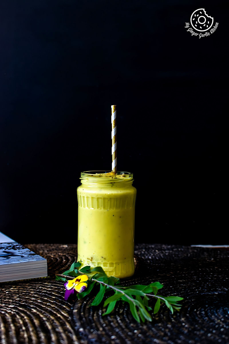 a yellow mango lassi drink with a straw in a jar