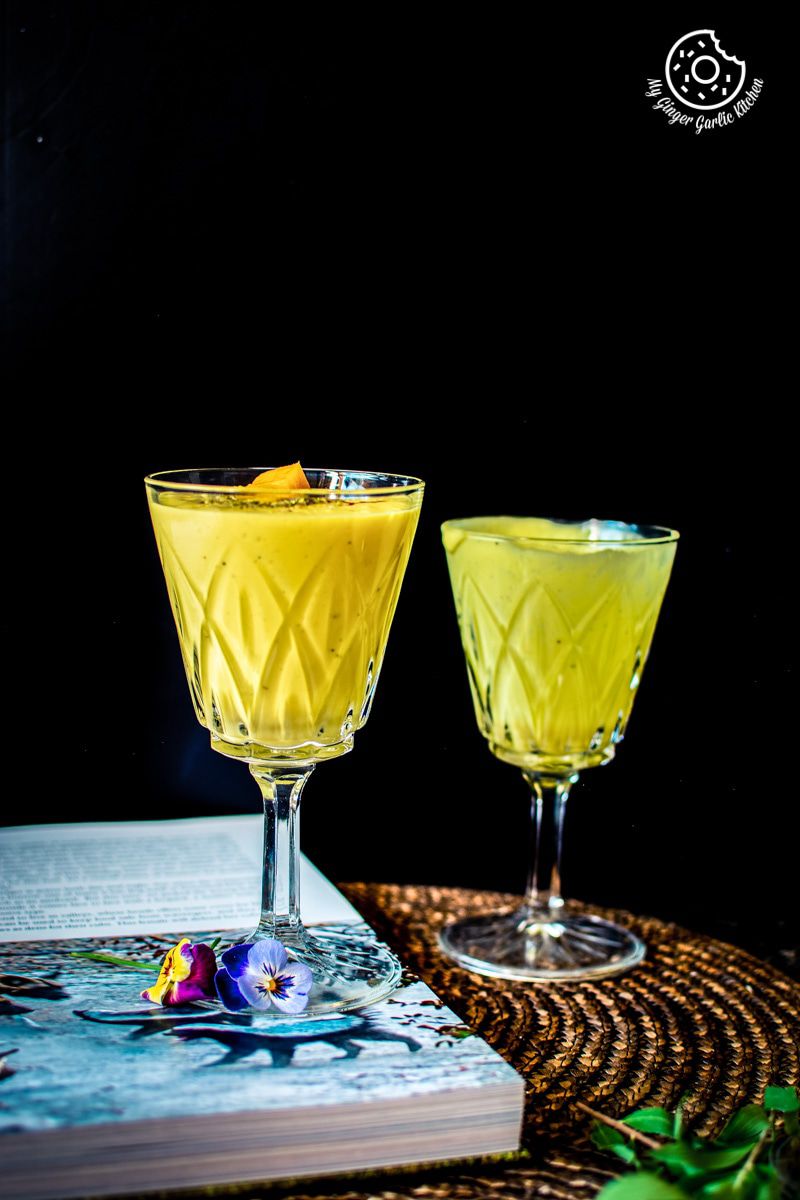 two glasses of mango lassi sitting on a table