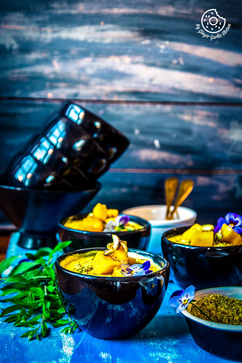 black bowls of mango shrikhand on a table on blue table 