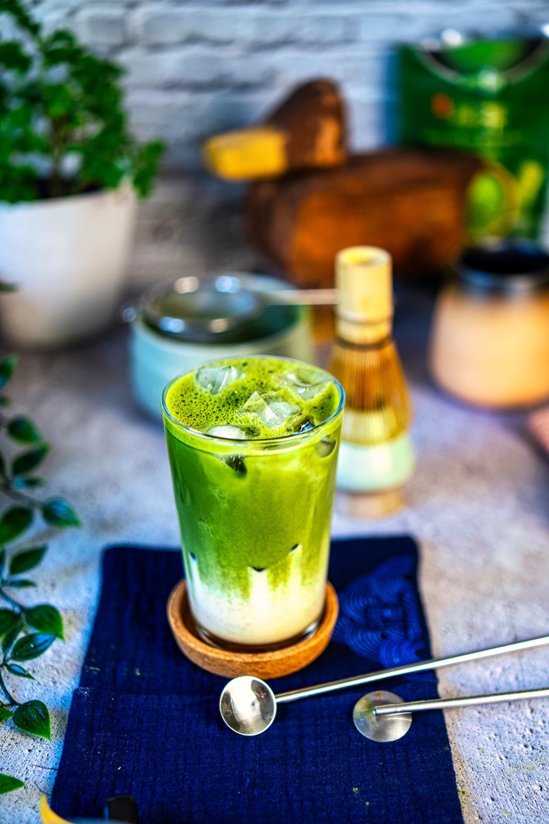 Iced matcha latte with frothy green matcha, ice, and creamy milk served with traditional matcha tools