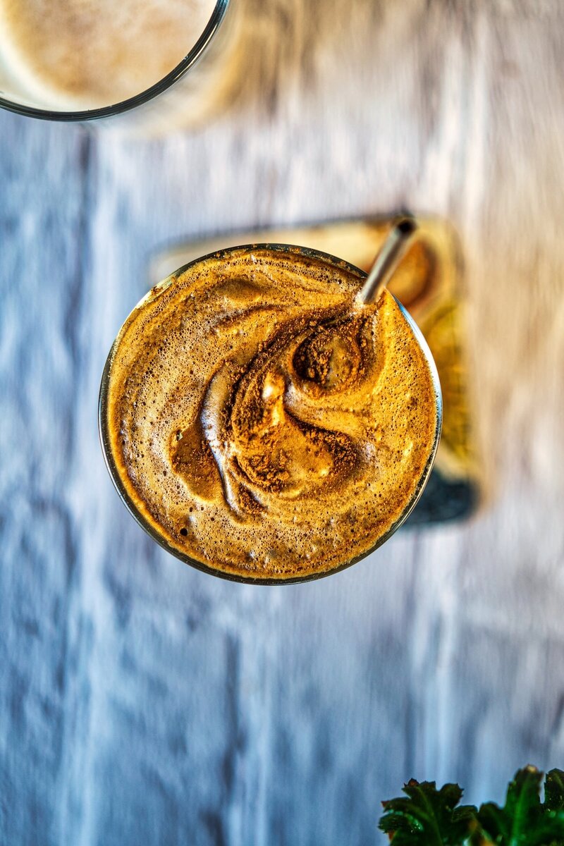 Top view of frothy dalgona coffee on iced oat milk latte with creamy foam swirl texture