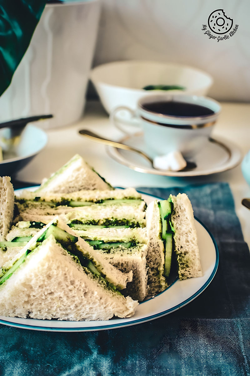there is a plate of indian cucumber chutney sandwiches on a table with a cup of coffee