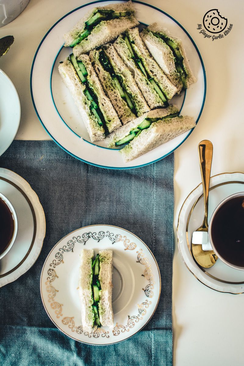 there are two plates of indian cucumber chutney sandwiches and a cup of coffee on the table