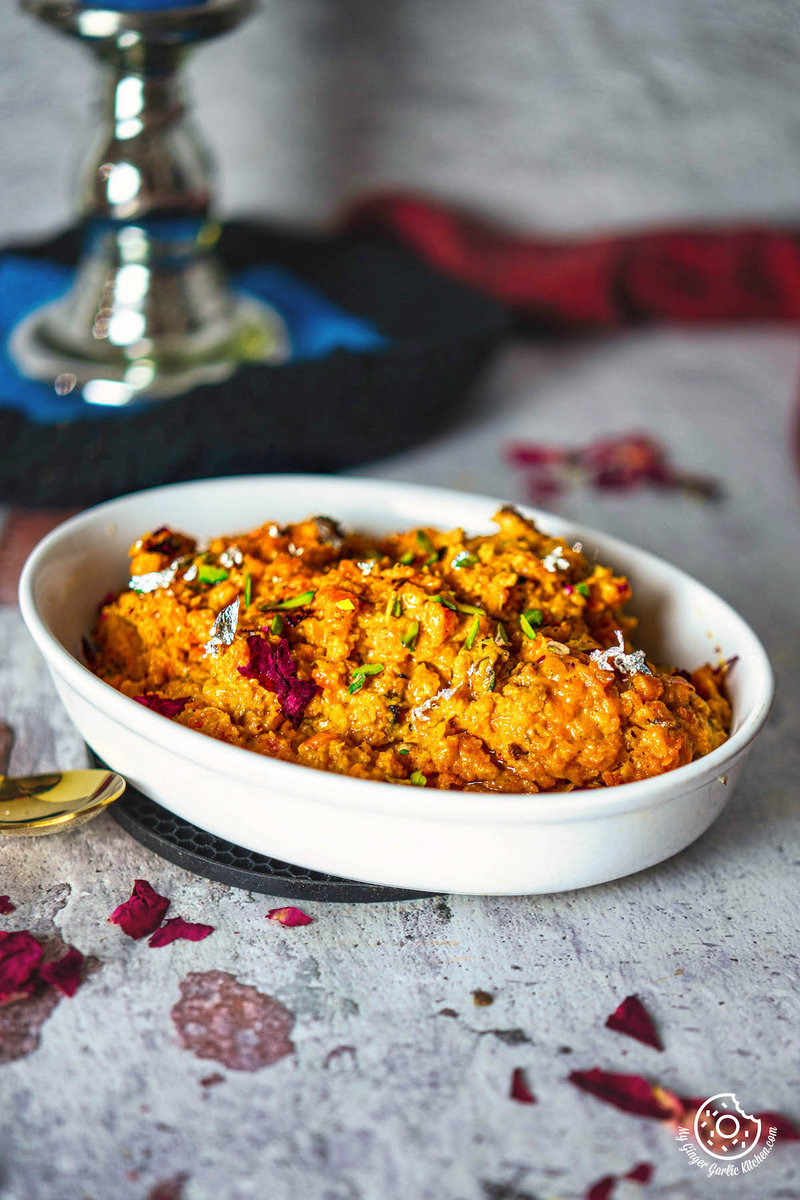 a bowl of instant gajar halwa on a table with a silver candle stand in background