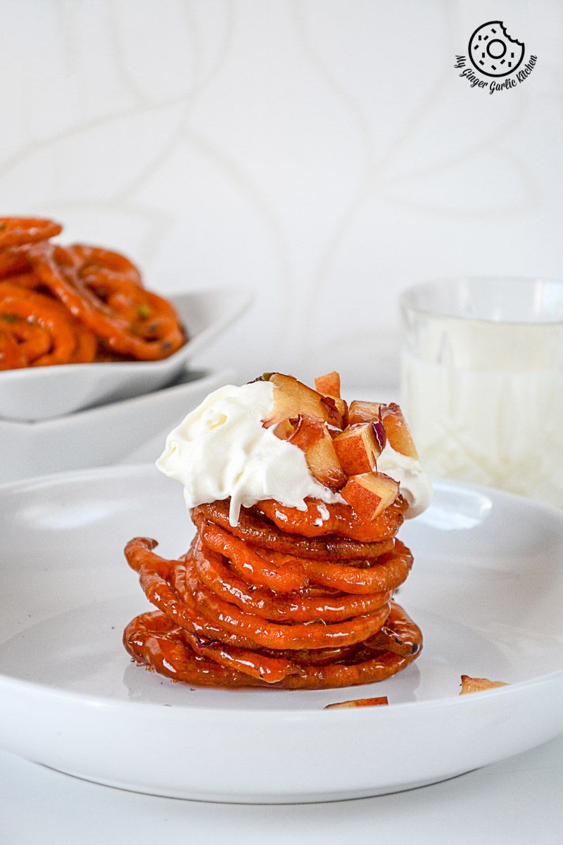 a stack of instant peach jalebi on a plate with whipped cream