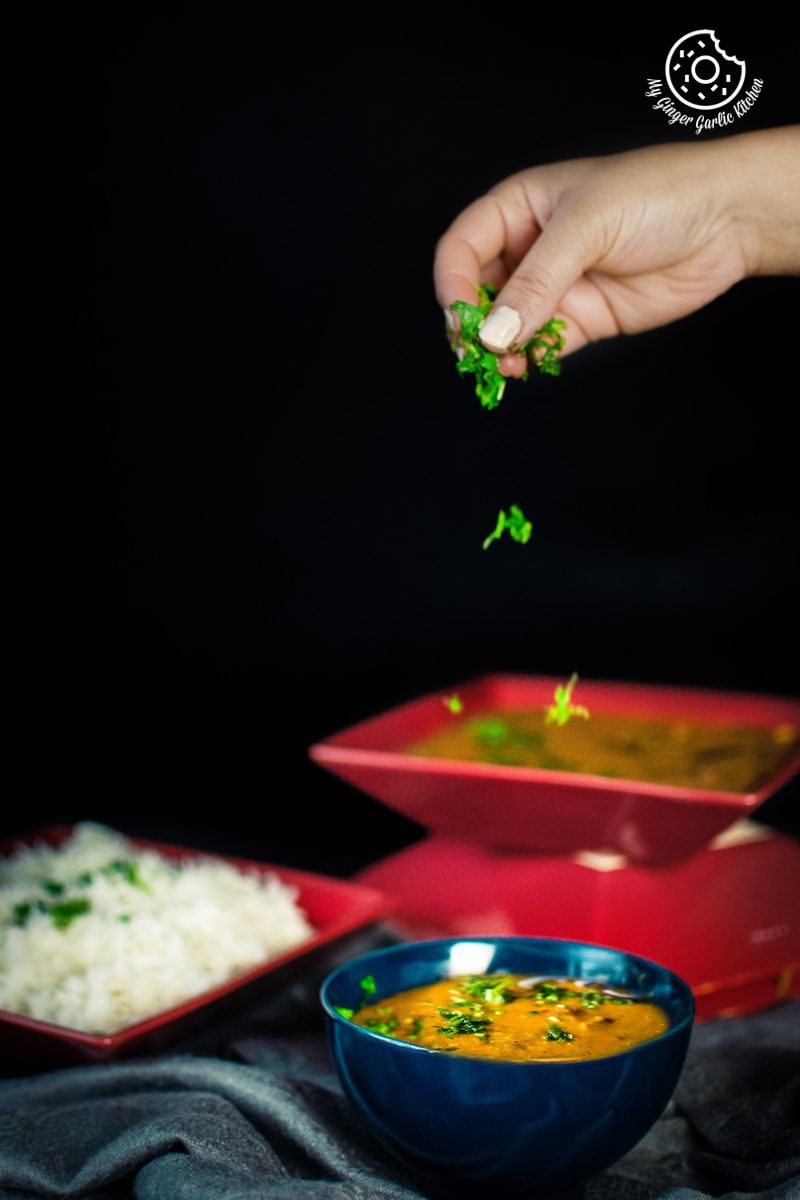 a hand sprinkling cilantro over masoor dal bowl