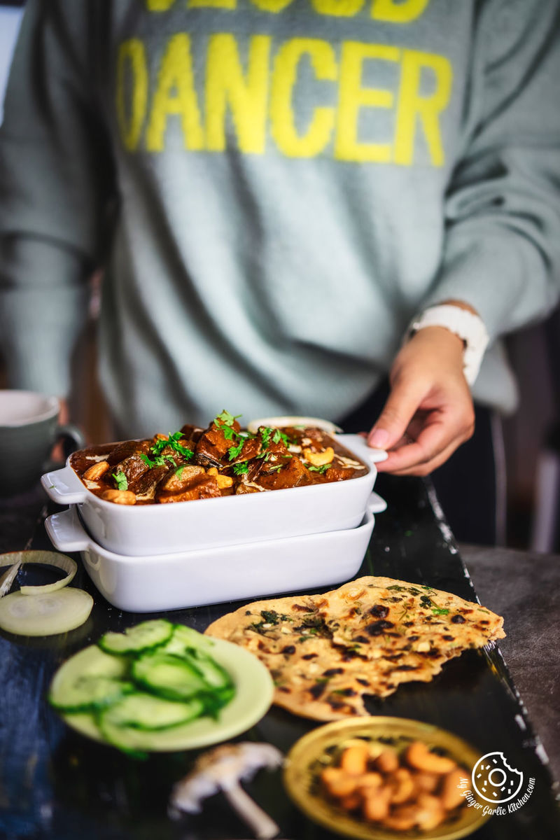 a female holding zucchini tofu curry topped with cilantro and cream served in a white rectangular casserole dish