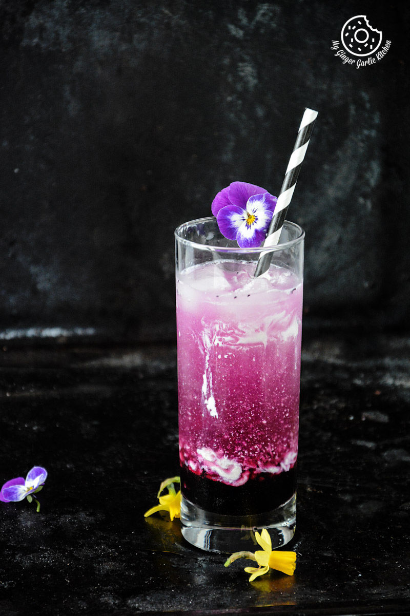 a purple drink italian cream soda with a flower in it and a straw
