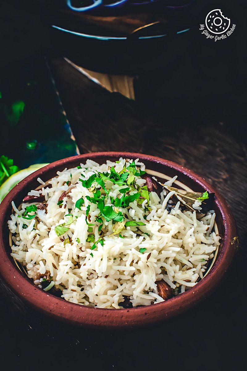 jeera rice served in a brown earthy bowl on a dark brown background