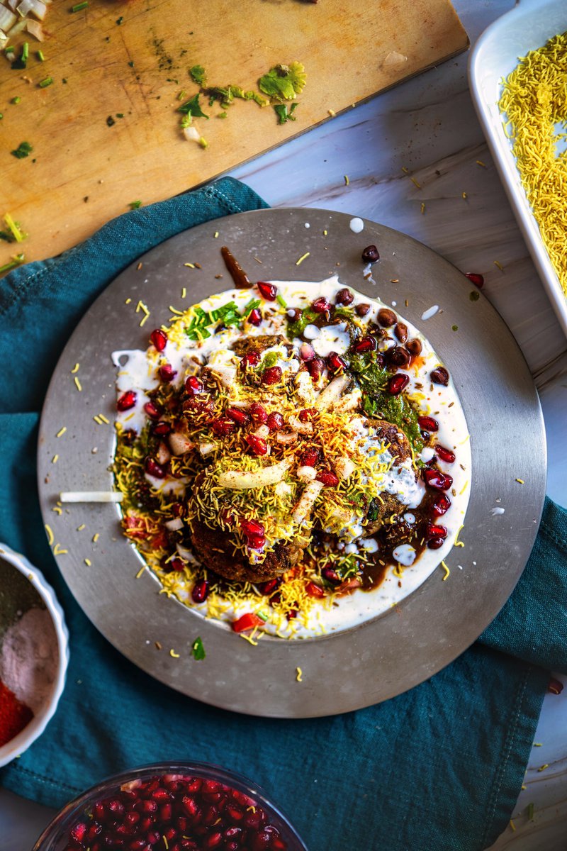 A plate of Kala Chana Tikki Chaat garnished with sev, pomegranate seeds, and fresh herbs.