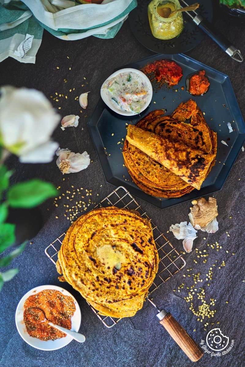 overhead shot od khichdi parathas along along with pickle, raita and chutney