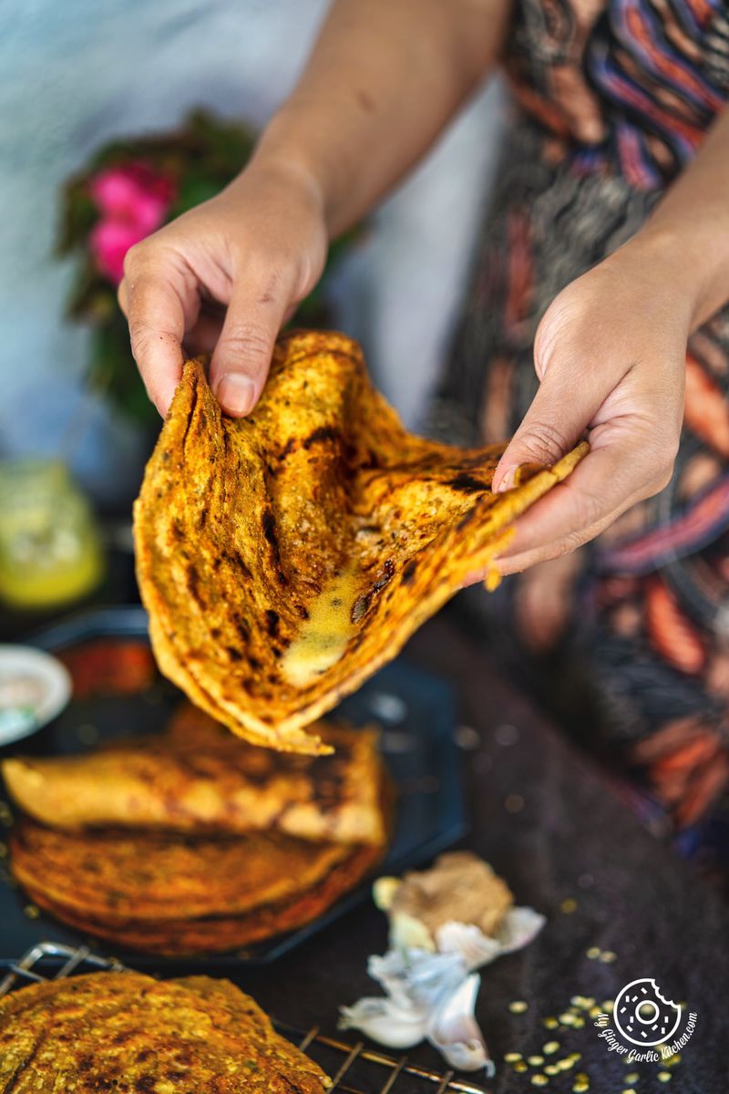 a female holding lachha khichdi paratha topped with ghee